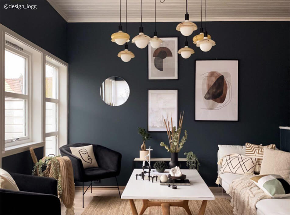 Всекидневна с тъмни стени, черни кадифени фотьойли, кръгло огледало, графични постери